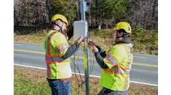 Virginia Tech Transportation Institute researchers (from left) Will Vaughn and Daniel Burdisso install part of the VTTI Smart Work Zone on a road sign. Photo by Jean Paul Talledo Vilela for Virginia Tech.