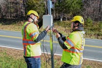 Virginia Tech Transportation Institute researchers (from left) Will Vaughn and Daniel Burdisso install part of the VTTI Smart Work Zone on a road sign. Photo by Jean Paul Talledo Vilela for Virginia Tech.